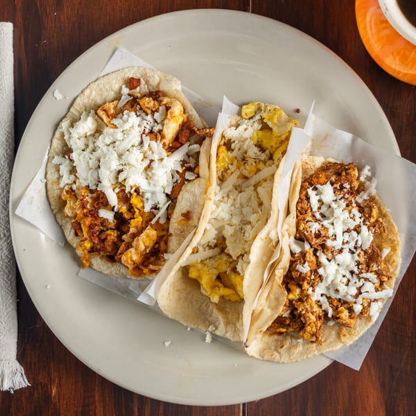Three Tacos Godoy breakfast tacos with scrambled eggs, chorizo, and crumbled white cheese.