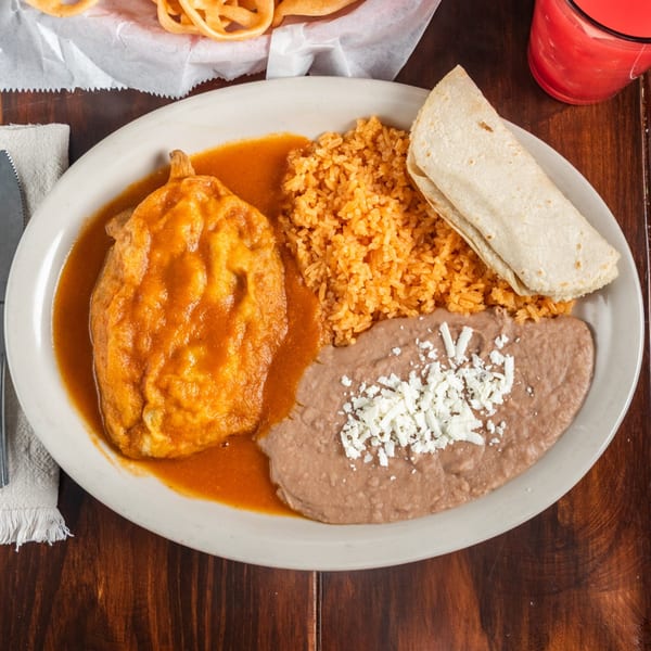 A Tacos Godoy Mexican plate with chile relleno, rice, refried beans with cheese, and a tortilla.